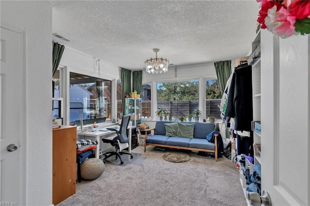 office area featuring a textured ceiling, a textured wall, a notable chandelier, carpet floors, and visible vents