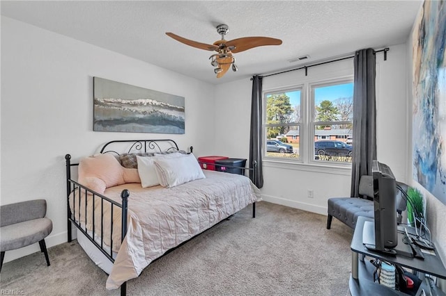 carpeted bedroom featuring a textured ceiling, a ceiling fan, visible vents, and baseboards