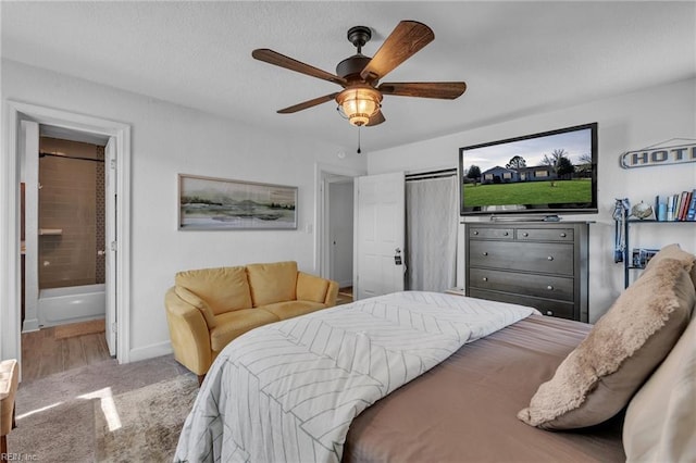 carpeted bedroom featuring ensuite bathroom, a ceiling fan, and baseboards