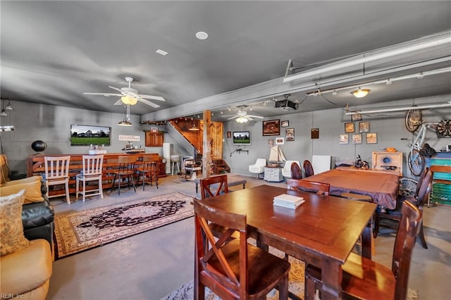 dining area featuring stairway, a ceiling fan, and finished concrete floors