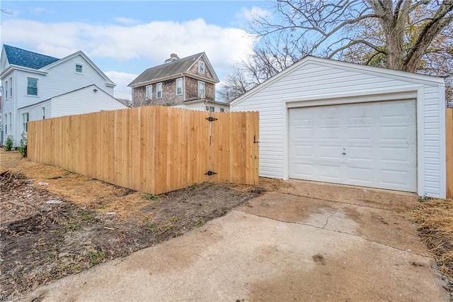 detached garage featuring driveway and fence