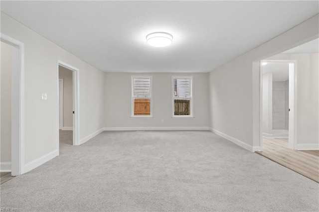 unfurnished room featuring light carpet and baseboards