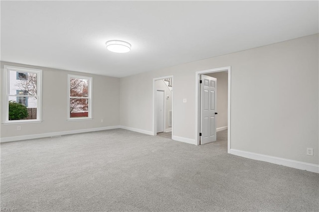 spare room featuring light carpet and baseboards