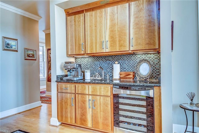 bar with light wood-style flooring, beverage cooler, a sink, baseboards, and backsplash