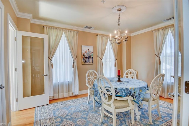 dining area featuring ornamental molding, a chandelier, visible vents, and wood finished floors