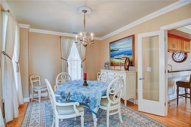 dining space with light wood finished floors, a chandelier, and ornamental molding