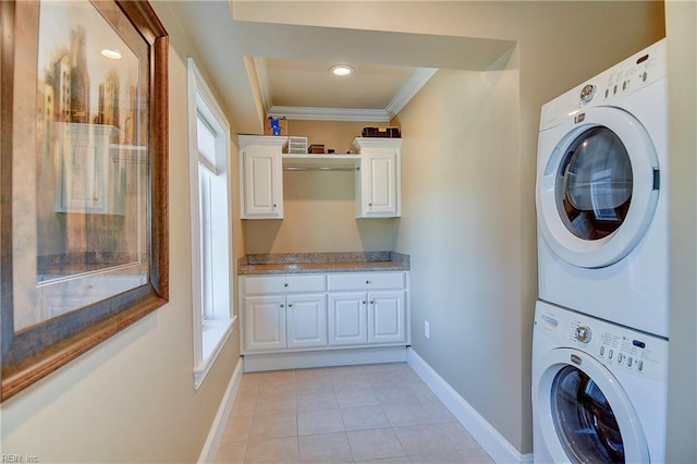 washroom featuring baseboards, ornamental molding, stacked washer / dryer, and light tile patterned flooring