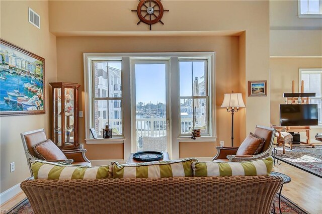 living area featuring baseboards, plenty of natural light, visible vents, and wood finished floors