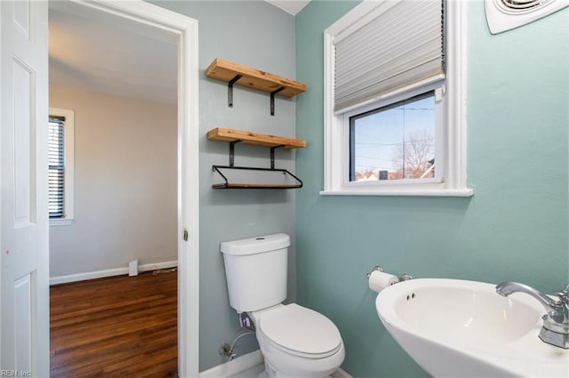 half bathroom featuring baseboards, a sink, toilet, and wood finished floors