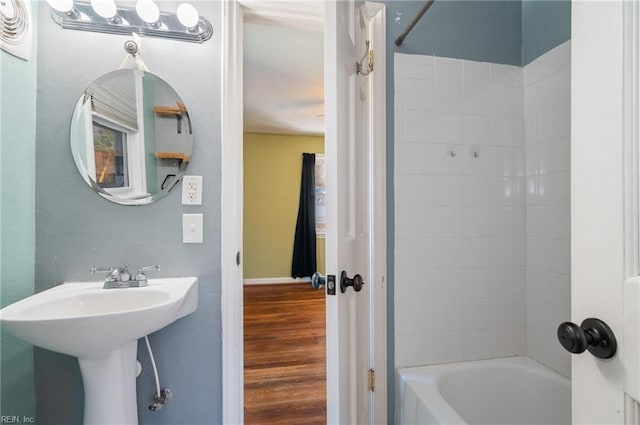 full bath with a sink, baseboards, wood finished floors, and bathing tub / shower combination