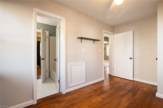 unfurnished bedroom featuring arched walkways, baseboards, and hardwood / wood-style flooring