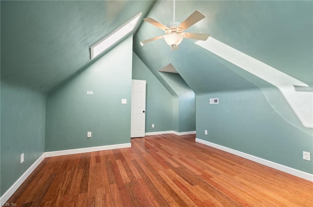 bonus room with ceiling fan, lofted ceiling with skylight, wood finished floors, and baseboards