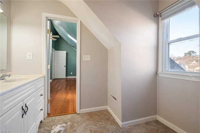 bathroom featuring lofted ceiling, baseboards, and vanity