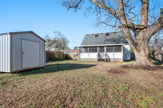 back of property featuring a storage shed, a lawn, a sunroom, a fenced backyard, and an outdoor structure