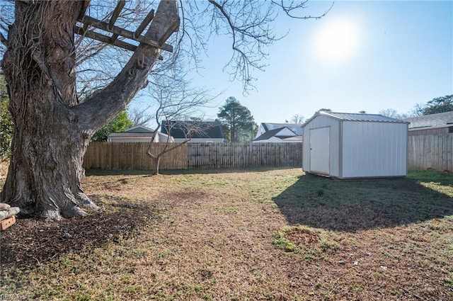 view of yard with a fenced backyard, an outdoor structure, and a storage shed