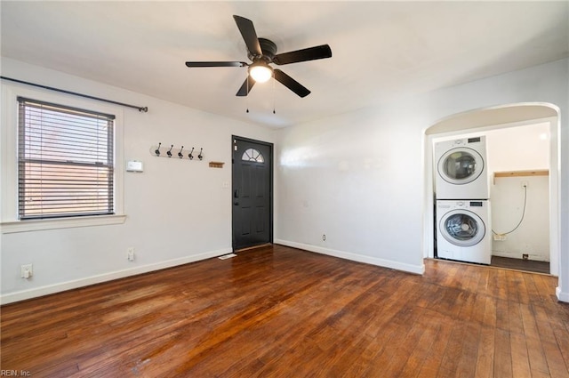 clothes washing area with laundry area, baseboards, a ceiling fan, wood-type flooring, and stacked washer / drying machine