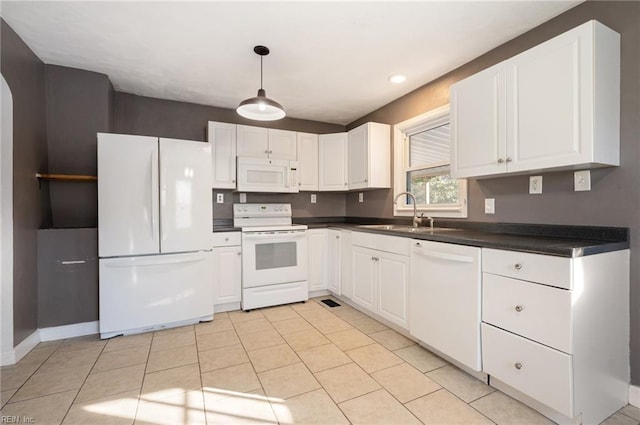 kitchen with light tile patterned floors, dark countertops, white cabinets, a sink, and white appliances