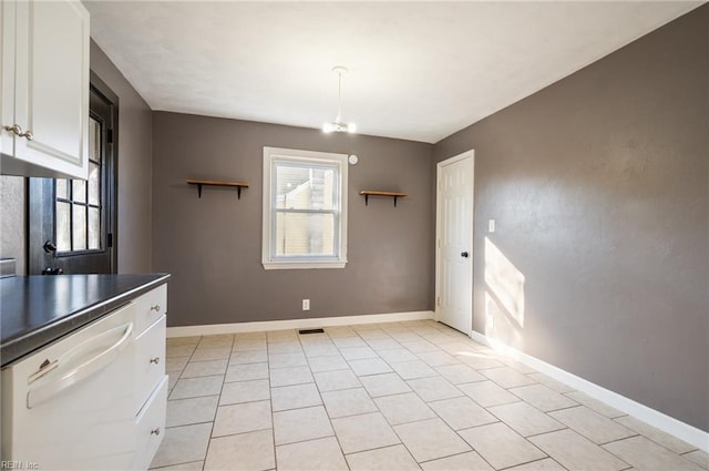 unfurnished dining area with light tile patterned floors, baseboards, visible vents, and a notable chandelier