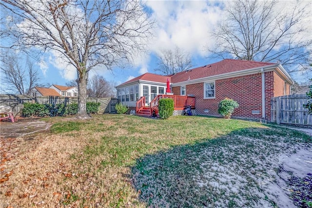 back of house with brick siding, a yard, a sunroom, a fenced backyard, and a wooden deck