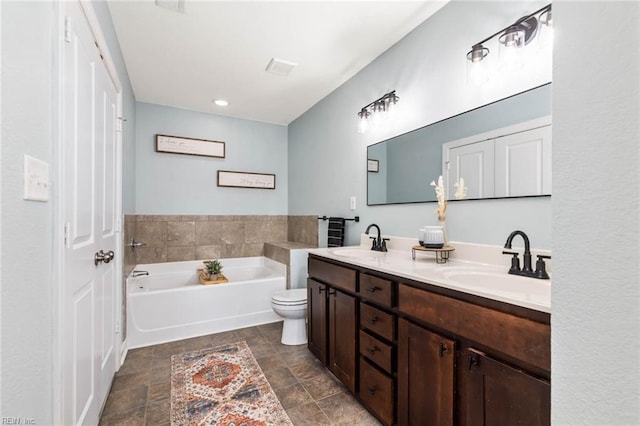 bathroom featuring double vanity, a sink, a bath, and stone finish flooring