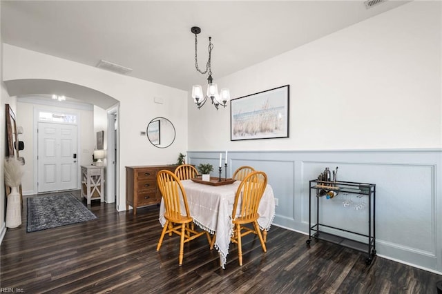 dining space with visible vents, arched walkways, wainscoting, wood finished floors, and a decorative wall