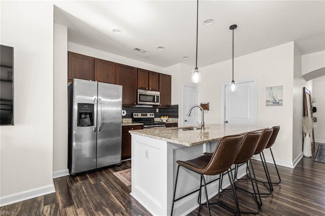 kitchen with stainless steel appliances, a sink, visible vents, dark brown cabinets, and decorative backsplash