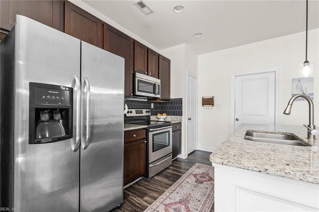 kitchen with dark brown cabinetry, a sink, visible vents, appliances with stainless steel finishes, and backsplash