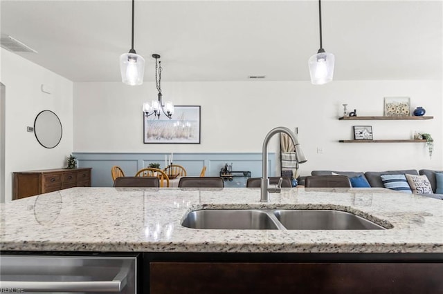 kitchen featuring light stone counters, open floor plan, visible vents, and a sink