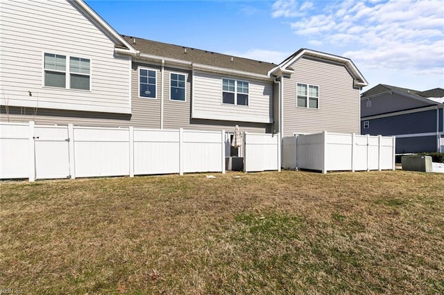 back of house with a lawn and fence