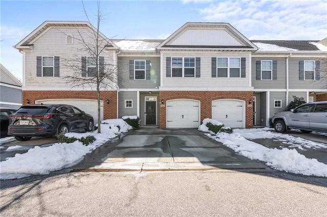 multi unit property with a garage, concrete driveway, and brick siding