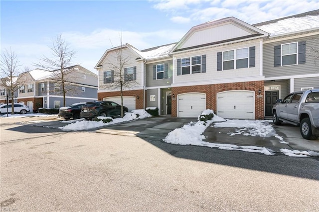 townhome / multi-family property with driveway, an attached garage, and brick siding