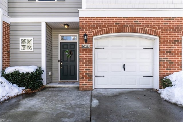 doorway to property featuring brick siding and driveway