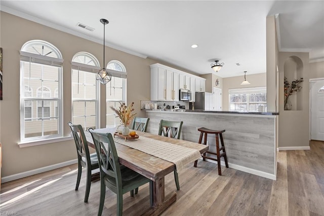 dining room with light wood-style floors, baseboards, and ornamental molding