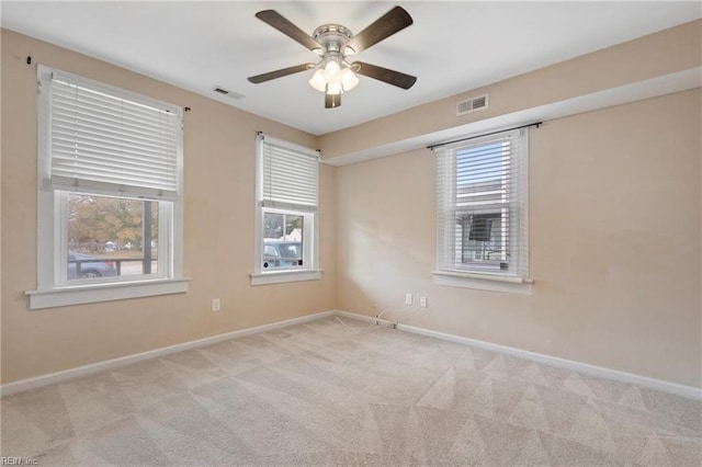 empty room featuring plenty of natural light, visible vents, and light colored carpet