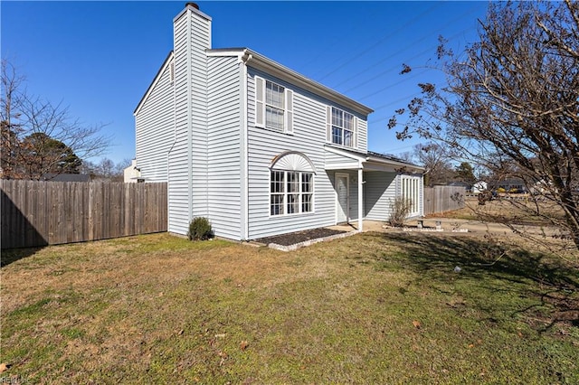 view of property exterior featuring a chimney, fence, and a lawn