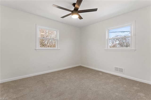 carpeted spare room featuring ceiling fan, visible vents, and baseboards