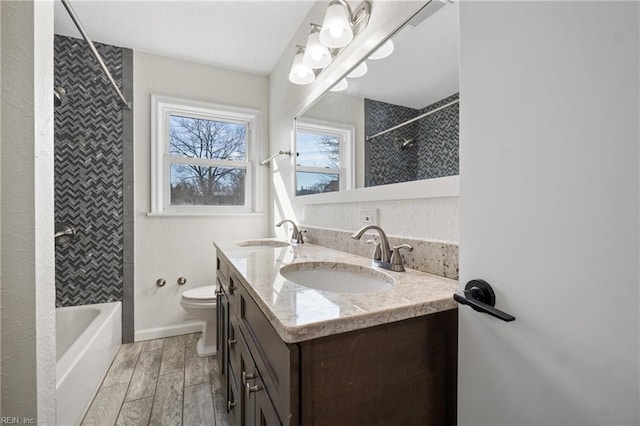 full bath with double vanity, a sink, toilet, and wood tiled floor