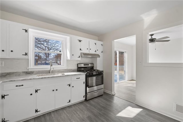 kitchen with under cabinet range hood, a sink, white cabinetry, backsplash, and gas stove