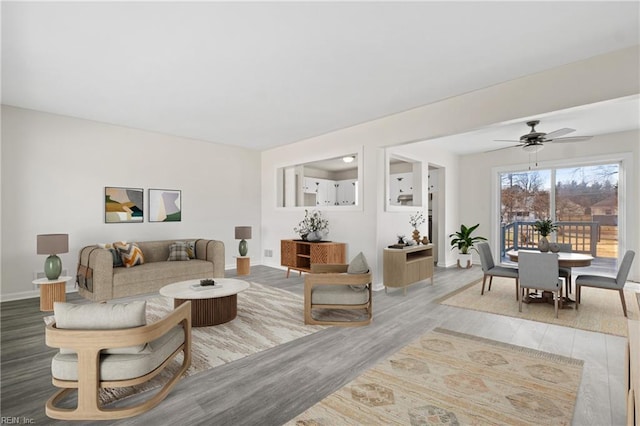 living room featuring a ceiling fan, light wood-type flooring, and baseboards