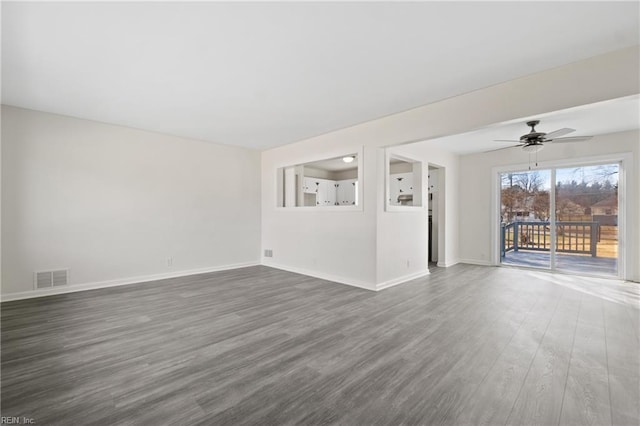 spare room with dark wood-style floors, visible vents, ceiling fan, and baseboards