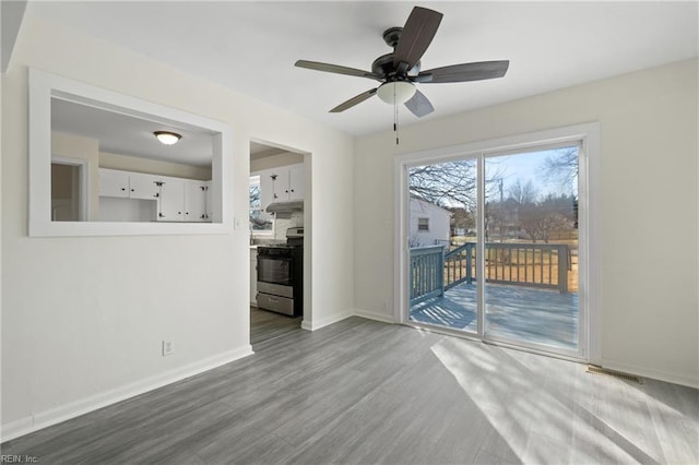 spare room featuring ceiling fan, wood finished floors, visible vents, and baseboards