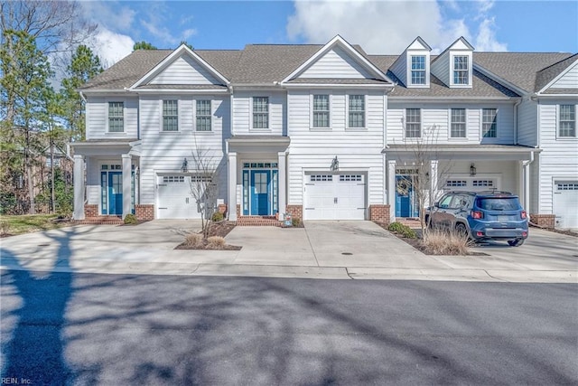 multi unit property with a garage, driveway, brick siding, and a shingled roof