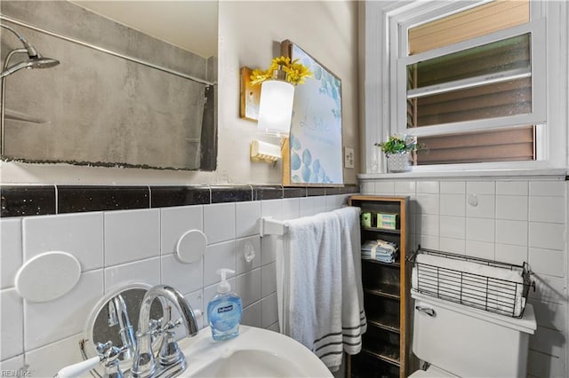 bathroom featuring a shower, a sink, tile walls, and toilet