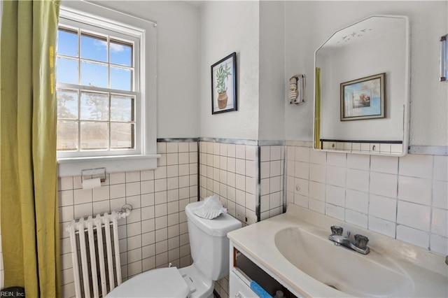 bathroom with wainscoting, toilet, radiator heating unit, vanity, and tile walls