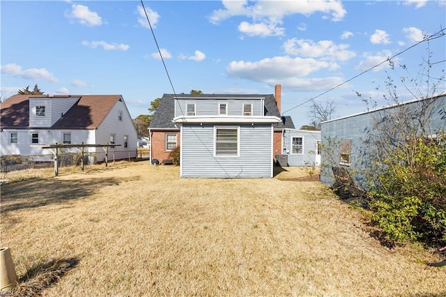 rear view of house featuring a yard, brick siding, and fence