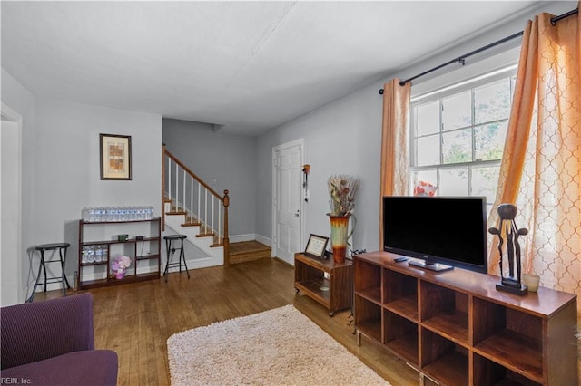 living area with stairs, baseboards, and dark wood finished floors