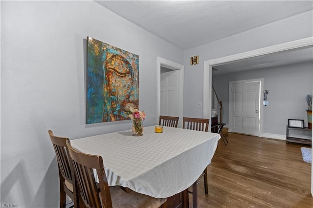 dining area with dark wood-type flooring and baseboards