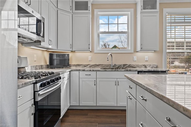 kitchen with appliances with stainless steel finishes, a sink, and light stone countertops