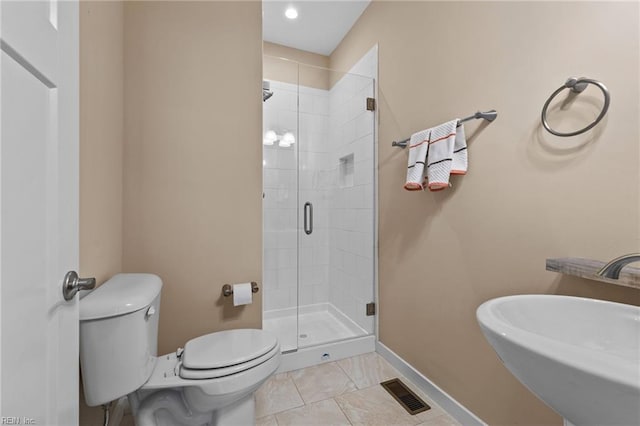 bathroom with visible vents, toilet, a stall shower, a sink, and baseboards