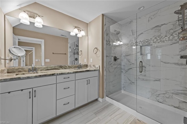 bathroom featuring marble finish floor, a sink, a marble finish shower, and double vanity